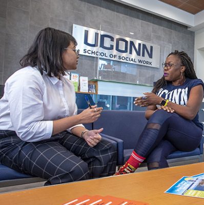 Ph.D. students having a conversation in the entryway of the School of Social Work (SSW). Sept. 14, 2022. (Sean Flynn/UConn Photo)
